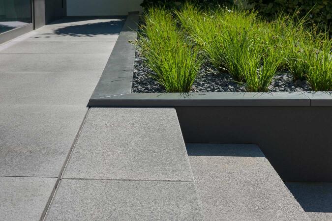 Umbriano Grauanthrazit gemasert in Kombination mit Tocano-Blockstufe Grauanthrazit gemasert mit gesägtem Stoß